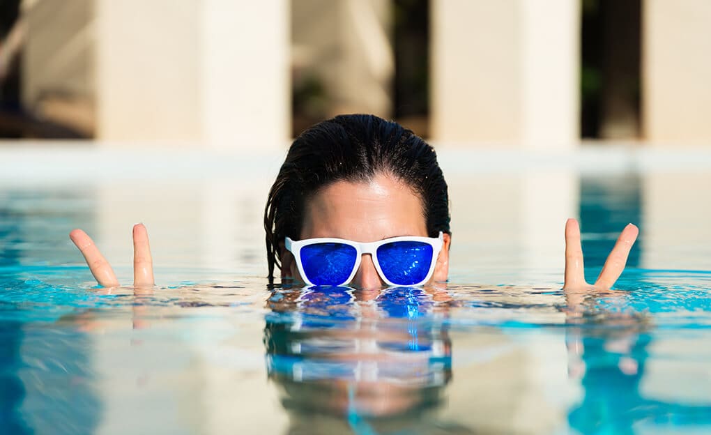 femme dans une piscine faisant le signe de la victoire