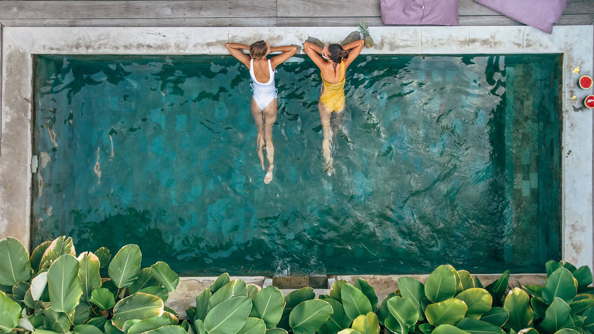 deux personnes allongés sur le rebord d'une piscine